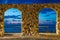 Sunset view of Tyrrhenian sea through stone arch gate in Cefalu, Sicily, Italy