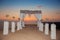 Sunset. Wedding ceremony arch with flowers decorative arrangement with white curtain on cliff above sea, sunrise outdoor summer p