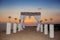 Sunset. Wedding ceremony arch with flowers decorative arrangement with white curtain on cliff above sea, sunrise outdoor summer p