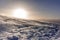 The sunset in winter during a wind storm with the snow being blown away on a peak near Lenzerheide in Switzerland