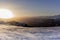 The sunset in winter during a wind storm with the snow being blown away on a peak near Lenzerheide in Switzerland