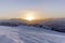 The sunset in winter during a wind storm with the snow being blown away on a peak near Lenzerheide in Switzerland