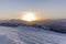 The sunset in winter during a wind storm with the snow being blown away on a peak near Lenzerheide in Switzerland