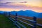 Sunset and wooden fence along pasture in the ranch, nature, summer landscape in carpathian mountains, spruces on hills, beautiful