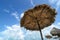 Sunshade umbrellas made of palm trees and blue cloudy sky