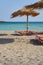 Sunshades on the tropical sandy beach against turquoise sea water.