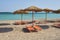 Sunshades on the tropical sandy beach against turquoise sea water.