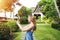 Sunshine portrait of young woman taking photo with tablet and smiling on green palms and house background in Thailand