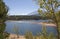 Sunshine sparkles on the water a fisheman stands on a point and aspen leaves turning yellow shimmer at Chrystal Reservoir half way