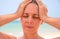 Sunstroke woman on tropical beach. Woman on hot beach with sunstroke. Headache from sun.