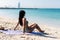 Suntan bikini woman sun tanning on beach lying down on beach towel on perfect blue ocean water background