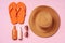 Suntan oil spray bottles and straw hat on pink background