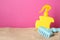 Suntan product and plastic beach toy on sand against pink background. Space for text