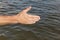 Suntanned male hand against of the water