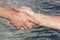 Suntanned male hands make handshake against a water