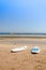 Sup boards on the sand of an empty beach/Surfboards standing upright in bright sun on the empty beach