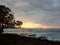 SUP Paddler ride waves as sunsets though the clouds off the coast of Turtle Bay