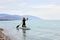 SUP Stand up paddle board. rear view on Young woman sailing on beautiful calm sea