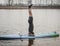 SUP YOGA, a man in a wetsuit doing yoga on a cloudy day, headstand on a paddle Board