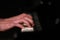 A super close image of a pianists fingers pressing the keys on a piano. isolated and illuminated in a dark background