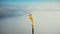 Super close-up aerial shot, golden St Michael statue on top of Mont Saint Michel castle fortress spire above cloudy sky.