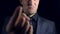 Super close-up of a man in black clothes on a black background. 4k. Slow motion. an evil man points a finger at the