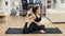 Super flexible young woman sitting on yoga mat