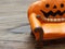 Super or giant worm crawling on orange miniature ceramic pumpkin couch or sofa over dark wooden surface