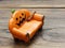 Super or giant worm crawling on orange miniature ceramic pumpkin couch or sofa over dark wooden surface