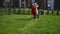 Super girl girl in red cloak mowing lawn in fenced house yard. Corded lawn mower