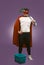 Super hero cleaner professional. Confidence man in red superhero costume with bucket and a mop stands on grape purple