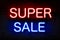 Super sale. Neon sign with luminous letters of red and blue on a black brick wall