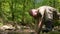 Super slow-mo. Man in khaki uniform washing his face from a forest stream with water