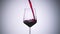 Super slow motion high speed shot of red wine flowing into a big bordeaux wineglass