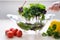 Super Slow Motion Shot of Flying Cuts of Colorful Vegetables and Water Drops woman washes a salad in a glass dish using