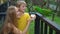 Super slowmotion shot of a mother and son in a bird park feed a group of green and red parrots with a milk