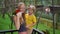 Super slowmotion shot of a mother and son in a bird park feed a group of green and red parrots with a milk