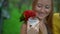 Super slowmotion shot of a mother and son in a bird park feed a group of green and red parrots with a milk