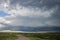 A supercell storm cloud hangs low in the sky over the prairie.