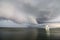 A supercell thunderstorm and shelf cloud loom over a lake.