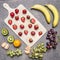 Superfoods and healthy lifestyle or detox diet food concept bananas, strawberries, light dark grapes, kiwi and tangerine on a