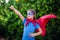 Superhero kid against green background outdoor. Childhood, success and and power concept