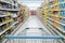 Supermarket aisle with empty blue shopping cart with customer defocus background