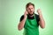 Supermarket employee with green apron and black t-shirt displeased face and gestures and talking on cellphone