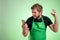 Supermarket employee with green apron and black t-shirt holding smartphone, texting, looking nervously