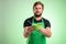 Supermarket employee with green apron and black t-shirt offers a bowl of soup