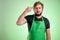 Supermarket employee with green apron and black t-shirt with showing shot head sign