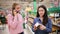 A supermarket and a mobile phone. Two young beautiful women are choosing products in the supermarket