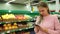 A supermarket and a mobile phone. Young beautiful woman uses mobile phone while shopping in store