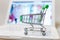 Supermarket shopping cart on laptop background close-up, macro, online shopping concept and purchasing power, consumer